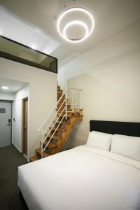 a bedroom with a white bed and a staircase at Haeundae Blue Story Hotel in Busan