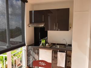 a kitchen with black cabinets and a sink and a window at Vacance au soleil ! studio Abricot 310 in La Trinité