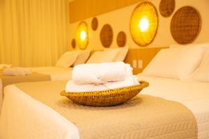 a basket of towels on a bed in a hotel room at Pousada Águas de Maragogi in Maragogi