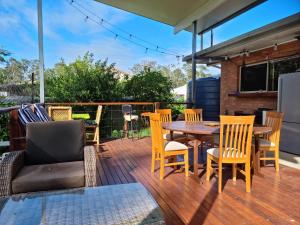 una terraza con mesa y sillas de madera, mesa y silla en Maryborough's Rainforest Retreat en Maryborough