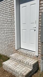 een witte deur op een stenen huis met trappen bij Private entrance apartment in Bentonville