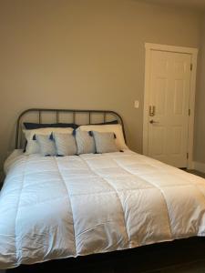 Elle comprend un grand lit avec des draps blancs et des oreillers bleus. dans l'établissement Private entrance apartment, à Bentonville