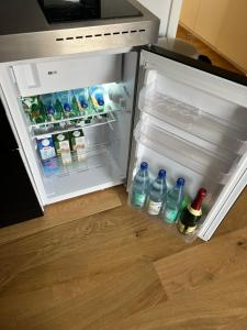 an open refrigerator with bottles of water and drinks at Köln City Stillvolle Apartment in Cologne