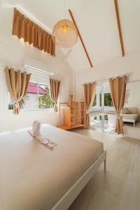 a bedroom with a large bed in a room with windows at Sunset Lover Beach Residence in Thongsala