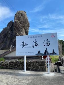 una gran señal frente a una montaña en お宿　弘法湯, en Kushimoto