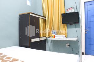 a room with a bed and a tv and a curtain at Snow White Residence near Grogol Mitra RedDoorz in Jakarta