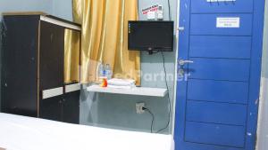 a room with a bed and a tv and a mirror at Snow White Residence near Grogol Mitra RedDoorz in Jakarta +16 photos
