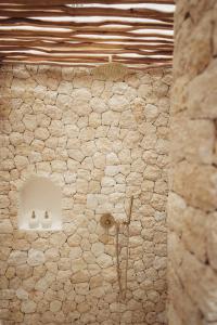 a stone wall with a shower in a room at Belajar Bali Boutique Hotel and Retreat in Canggu
