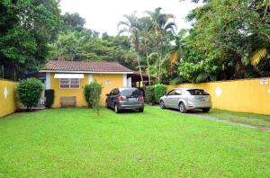 博拉塞亞的住宿－Chalés Boraceia Duda，两辆汽车停在房子前面的院子内