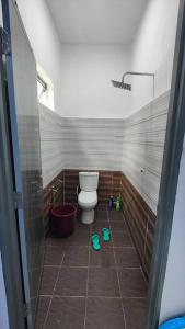 a bathroom with a toilet and a tiled floor at Homestay D Paya Jauh in Temerloh