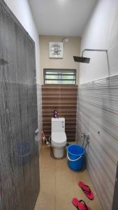 a bathroom with a toilet and a blue bucket at Homestay D Paya Jauh in Temerloh