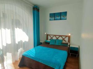 Schlafzimmer mit einem Bett mit blauer Bettwäsche und einem Fenster in der Unterkunft Appartement Cauterets, 3 pièces, 6 personnes - FR-1-234-301 in Cauterets