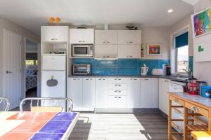 a kitchen with white cabinets and a table at Elevated two bedroom apartment in Arrowtown