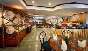 マニラにあるBerjaya Makati Hotelのテーブルと椅子のあるレストラン、ビュッフェ