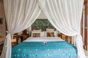 a bedroom with a large bed with white curtains at Baby Melon Villas in Seminyak