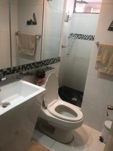 Baño blanco con aseo y lavamanos en Habitacion Cama Queen, en Bogotá