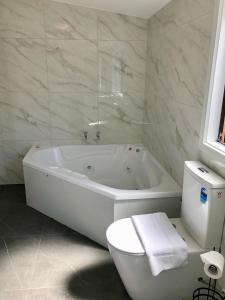 a white bathroom with a tub and a toilet at Pure Motel in Rotorua