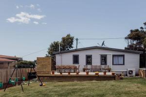 a house with a large deck in a yard at Bask - Family Friendly Home in Bicheno