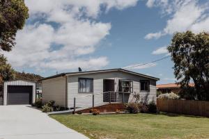 a small house in a yard with a driveway at Bask - Family Friendly Home in Bicheno