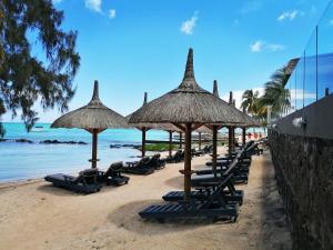 uma fila de cadeiras de praia e guarda-sóis numa praia em Wonders Beach Boutique Hotel em Mont Choisy