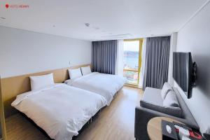 a hotel room with two beds and a flat screen tv at Hotel Kenny Yeosu in Yeosu