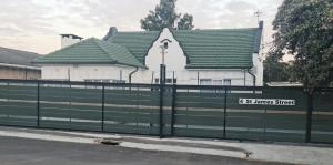 a green fence in front of a white building at Hasate Guest House ,4 st james street Oakdale Belliville Cape Town South Africa in Cape Town