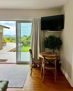 Zimmer mit einem Tisch und Stühlen sowie einer Glasschiebetür in der Unterkunft Wairimu View Lodge in Waipu