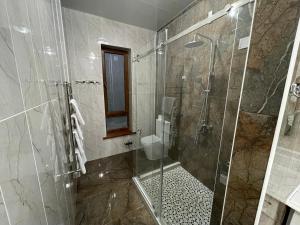 W łazience znajduje się prysznic ze szklanymi drzwiami. w obiekcie Жк Керуен Сарай w mieście Türkistan
