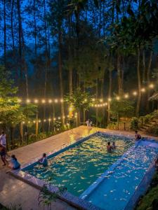 un gruppo di persone in una piscina di notte di Kampung Rimba by Anrha a Bogor