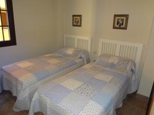 two twin beds in a bedroom with two pictures on the wall at Apartamentos Solmares in Isla Canela