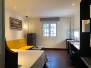 een woonkamer met een gele bank en een keuken bij My Stay Hotel & Apartment in Ho Chi Minh-stad