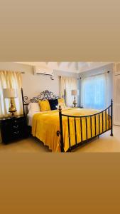 a bedroom with a large bed with yellow sheets and a window at Isle Be Back Villa in Priory