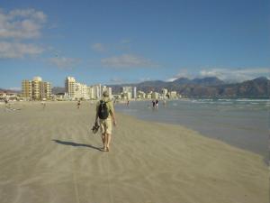 a man walking on the beach with a backpack at Ocean Elephant Beach Apartment in Strand