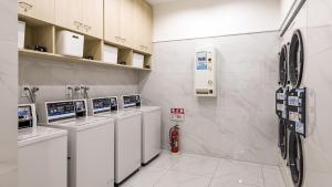 - une buanderie avec une rangée de lave-linge et de sèche-linge dans l'établissement Toyoko Inn Kita-toda-eki Higashi-guchi, à Toda