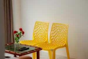 zwei gelbe Stühle neben einem Tisch mit einer Blumenvase in der Unterkunft Calais7 in Thodupuzha