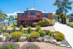 a house with a balcony and a yard with bushes at Bay of Fires Great Escape in Binalong Bay