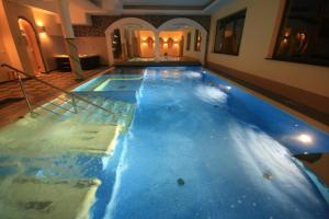 a large swimming pool with blue water in a building at Dwór Ostoia in Rymanów