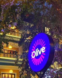 a purple alive sign on a pole in front of a building at Olive Calangute Niwasa - by Embassy Group in Calangute