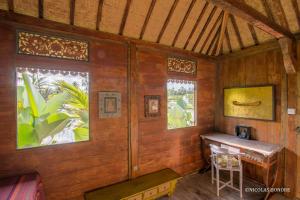 a wooden room with a table and two windows at Hati Padi Cottages in Ubud