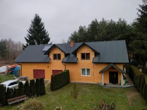 a house with a black roof on a yard at Zacisze Tanwi in Pisklaki