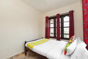 a bedroom with a bed and a window with red curtains at AAdya. Homestay in Madikeri