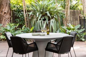 una mesa blanca con sillas y una copa de vino en 9 Little Cove Road, Noosa Heads - Private Slice of Paradise, en Noosa Heads