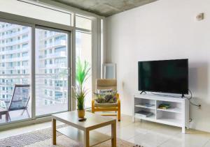 een woonkamer met een flatscreen-tv en een tafel bij Two Bedroom Apartment with Pool At Midblock Miami in Miami