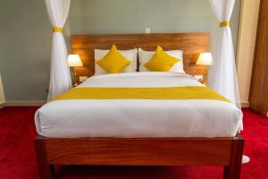 ein Schlafzimmer mit einem großen Bett mit gelben Kissen in der Unterkunft Burch's Resort Naivasha in Naivasha