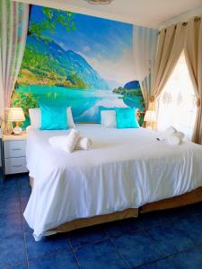 - une chambre avec un grand lit orné d'un tableau représentant un lac dans l'établissement Queensburgh B&B or Self Catering, à Durban