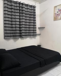 uma cama preta num quarto branco com uma janela em E3 Summer Homestay 夏之屋 em Kudat