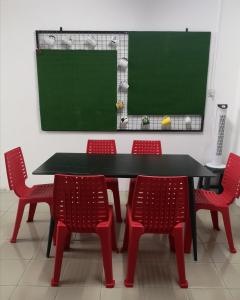 una mesa negra con 4 sillas rojas y una pizarra en E3 Summer Homestay 夏之屋, en Kudat
