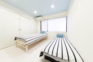 two beds in a white room with a window at Junfukuya(153-1,2) in Osaka