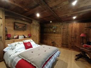 1 dormitorio con 1 cama en una habitación con paredes de madera en La montagnarde des Sapins Blancs, en Vacheresse
