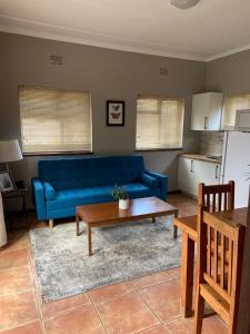 a living room with a blue couch and a table at Eike Cottage in George